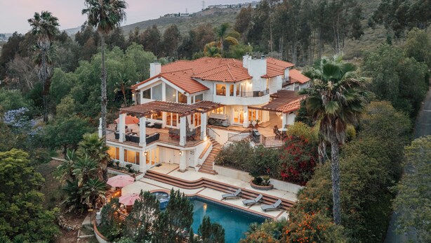 Una casa grande con varios niveles, piscina y jardín ajardinado.