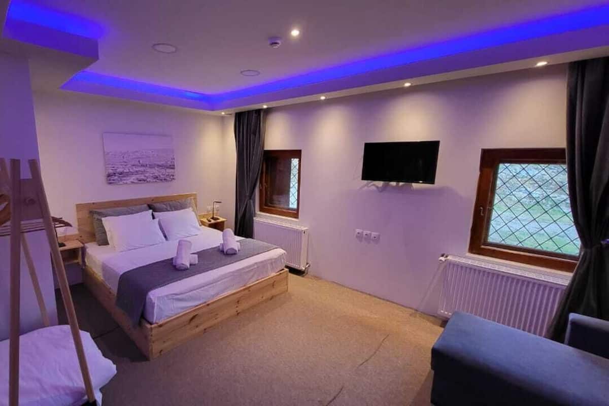 Quarto com cama, uma cadeira, televisão e janela.