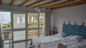 A bedroom with a large bed, a view through the glass door, and a chair by the window. - w* | Modern 5BR with Private Pool in Paracas (Paracas)