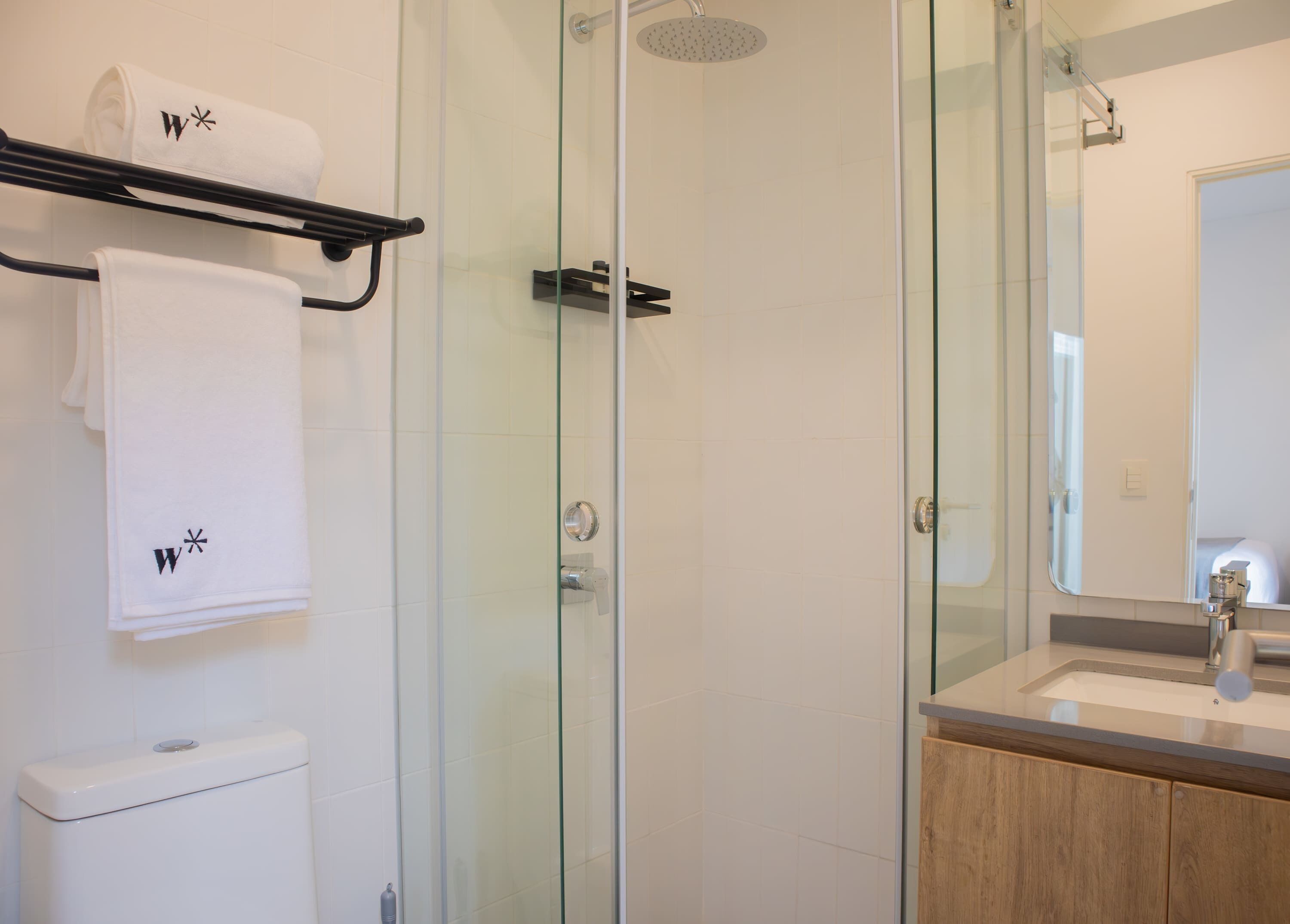 Un baño moderno con cabina de ducha de vidrio, inodoro y tocador con espejo.