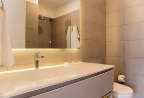 Une salle de bain moderne avec un grand lavabo, un miroir et des toilettes.