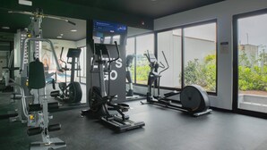 Un gimnasio con máquinas de cardio, equipo de levantamiento de pesas y un espejo grande.