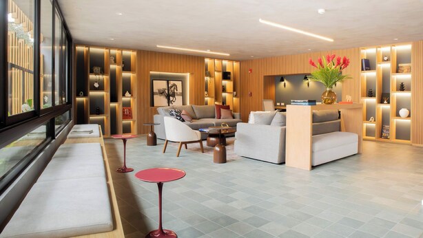 Un vestíbulo de hotel moderno con zonas de estar, una recepción y un amplio ventanal con vistas.