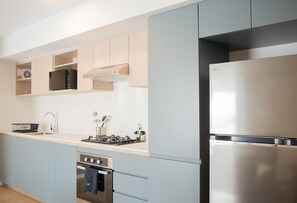 Een moderne keuken met lichtblauwe kastjes, een roestvrijstalen koelkast, een inbouwoven en een gasfornuis.