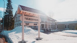Um edifício com uma placa que diz "VARDSHUS" e "MAT RUM", indicando um hotel ou pousada.