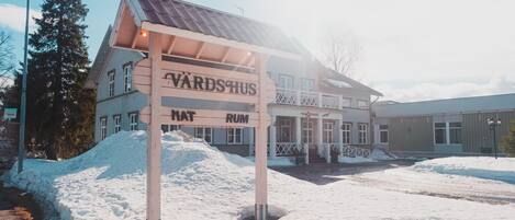 Ein Gebäude mit einem Schild, auf dem „VARDSHUS“ und „MAT RUM“ stehen, was auf ein Hotel oder ein Gästehaus hindeutet.