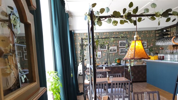 Interior de restaurante com mesas e cadeiras de madeira e um balcão.