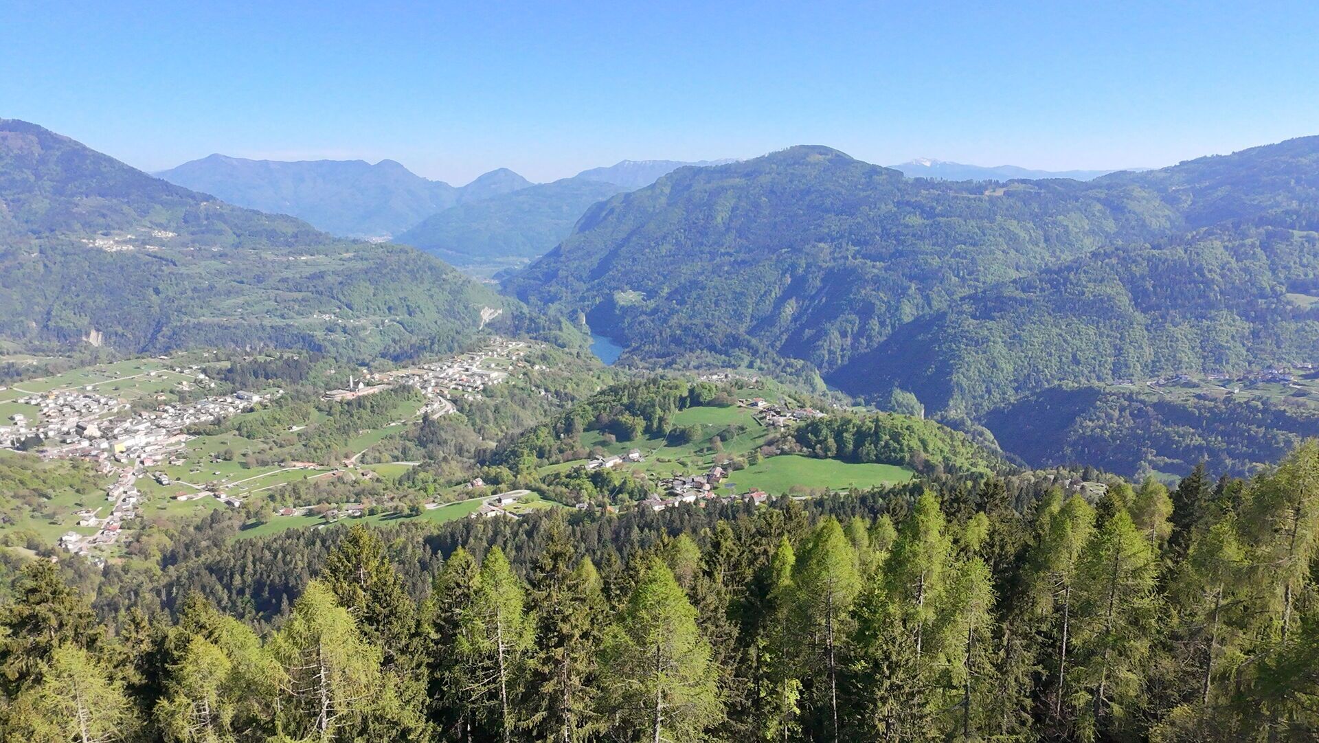 A mountainous landscape with a valley, dense forest, and a small town.