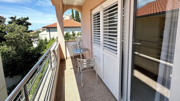 A balcony with a table and chairs, a sliding glass door, and a view of the neighborhood. - Apartman Velvet Vista 3 (Novi Vinodolski)