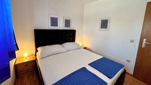 A hotel room with a bed, two bedside tables, and wall-mounted pictures. - Apartman Velvet Vista 3 (Novi Vinodolski)