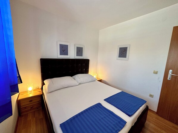 A hotel room with a bed, two bedside tables, and wall-mounted pictures.