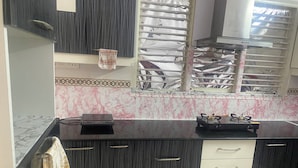 Uma cozinha com painel de parede em mármore, armários preto e branco, fogão a gás e um varal de secagem.
