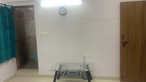 Quarto com mesa de vidro, porta de madeira e tomadas.