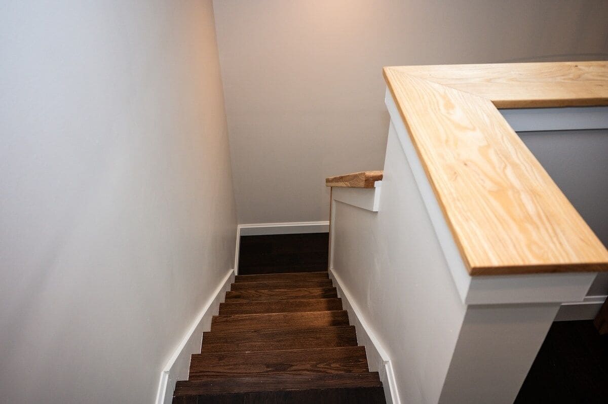 Una escalera con escalones de madera y paredes blancas.