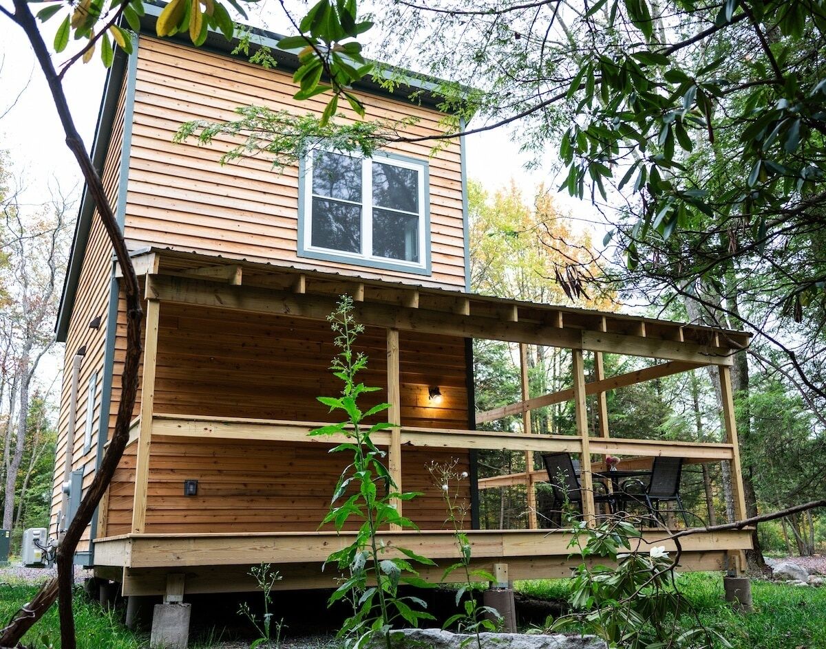 A wooden cabin with a balcony, surrounded by trees.