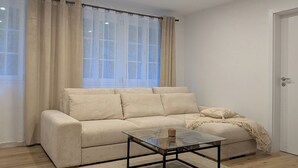 Un salon moderne avec un canapé beige, une table basse en verre et un parquet en bois.