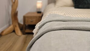 Une chambre à coucher comprenant un lit, une table de chevet, une lampe et une œuvre d’art accrochée au mur.