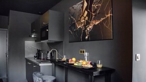 A modern kitchen with a marble backsplash, a stainless steel countertop, and a bar area with stools.