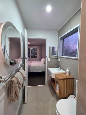 Een moderne badkamer met toilet, wastafel en spiegel.