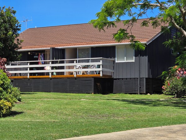 A two-story house with a balcony, a red-tiled roof, and a grassy yard. - Fletcher Christian Apartments - Isabella Suites (Burnt Pine)