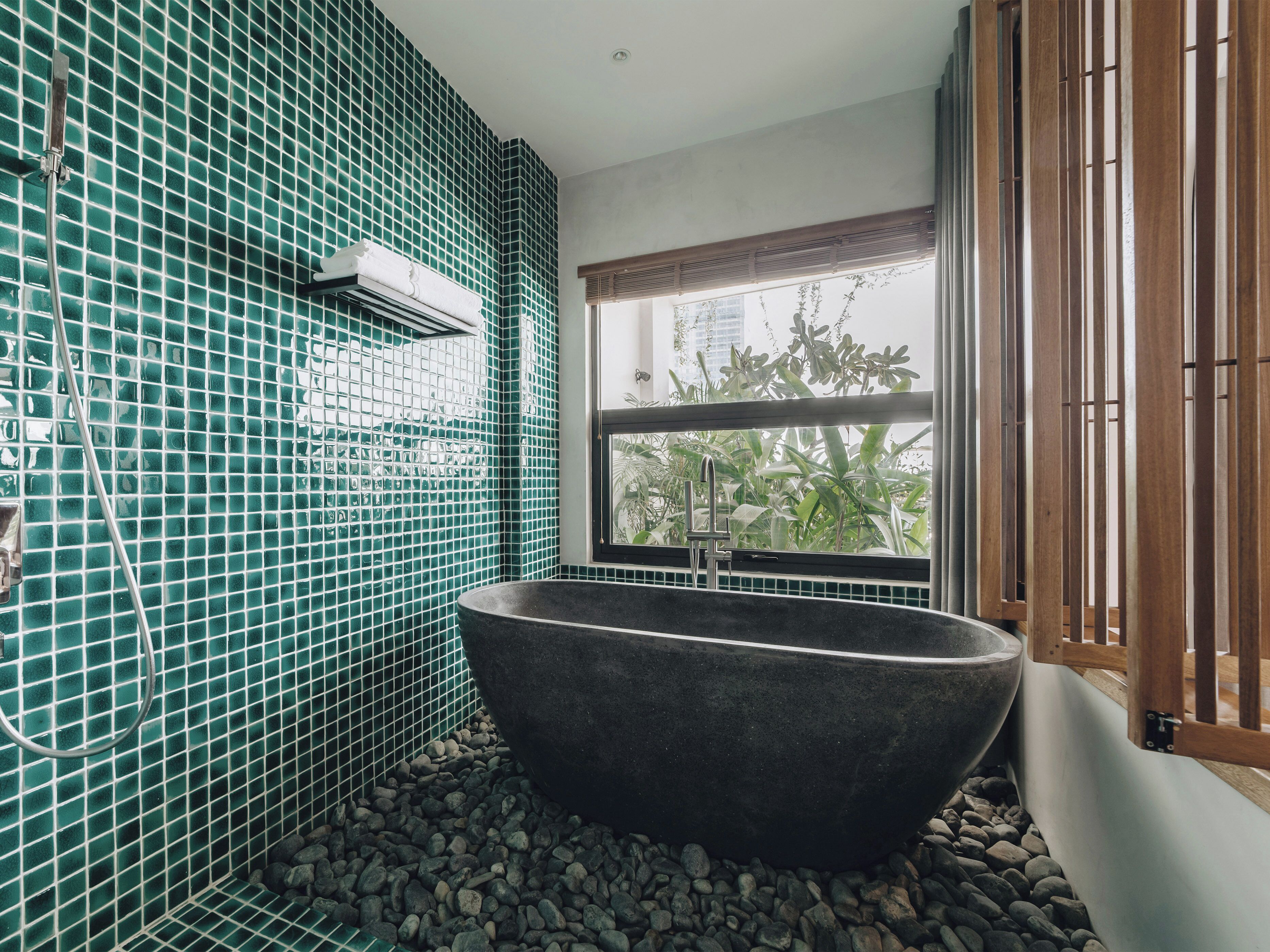 Une salle de bain avec une baignoire sur pieds, une fenêtre donnant sur un paysage verdoyant et un mur carrelé.