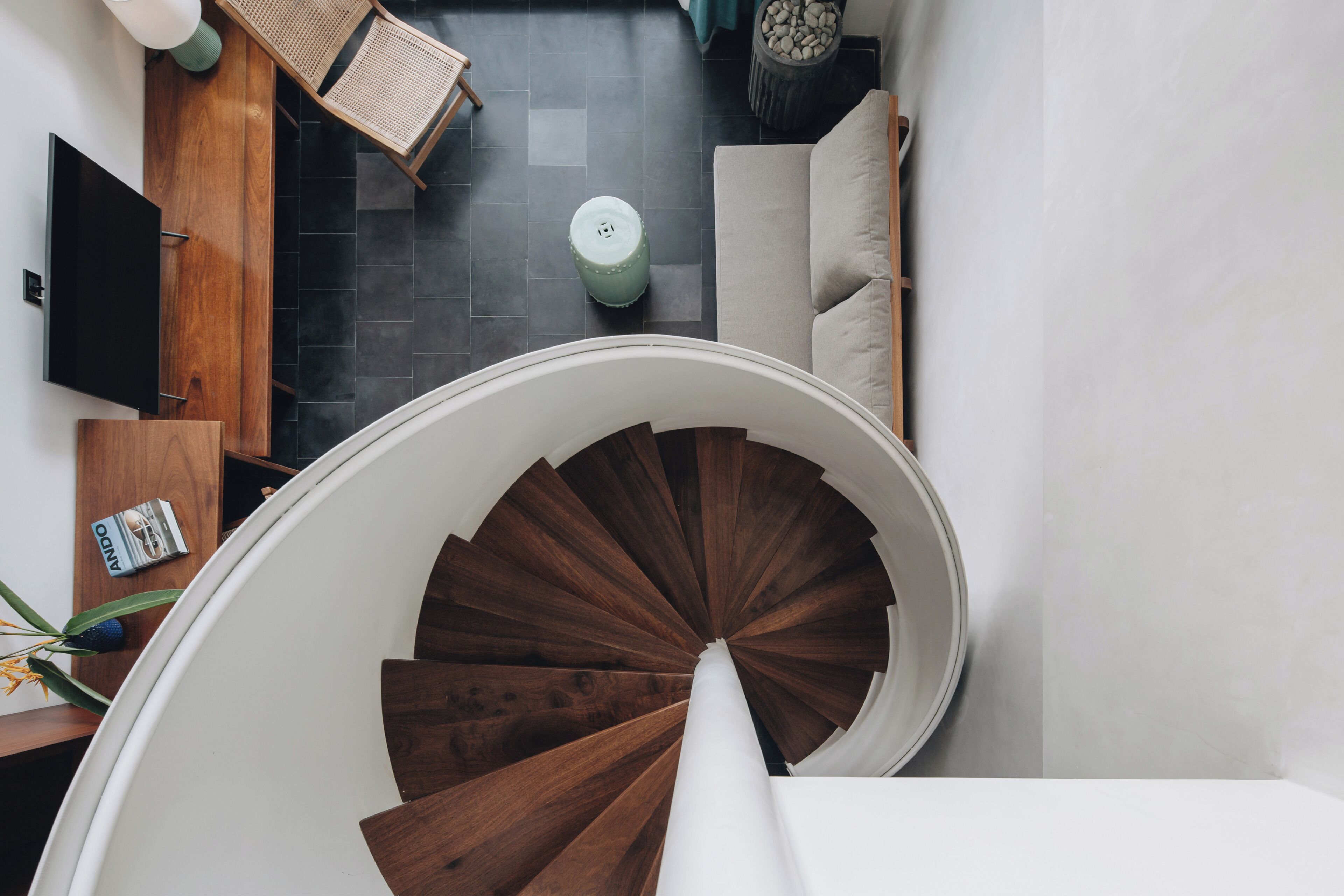 A spiral staircase with wooden steps leading to a white wall.