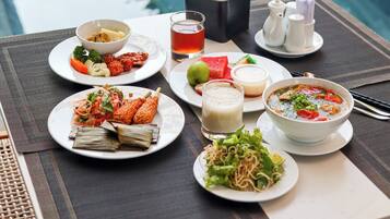 A dining table with various dishes, a beverage, and condiments, set against a poolside view.
