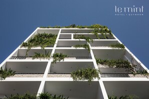 Un hôtel moderne doté de nombreux balcons, chacun agrémenté de plantes et de verdure.