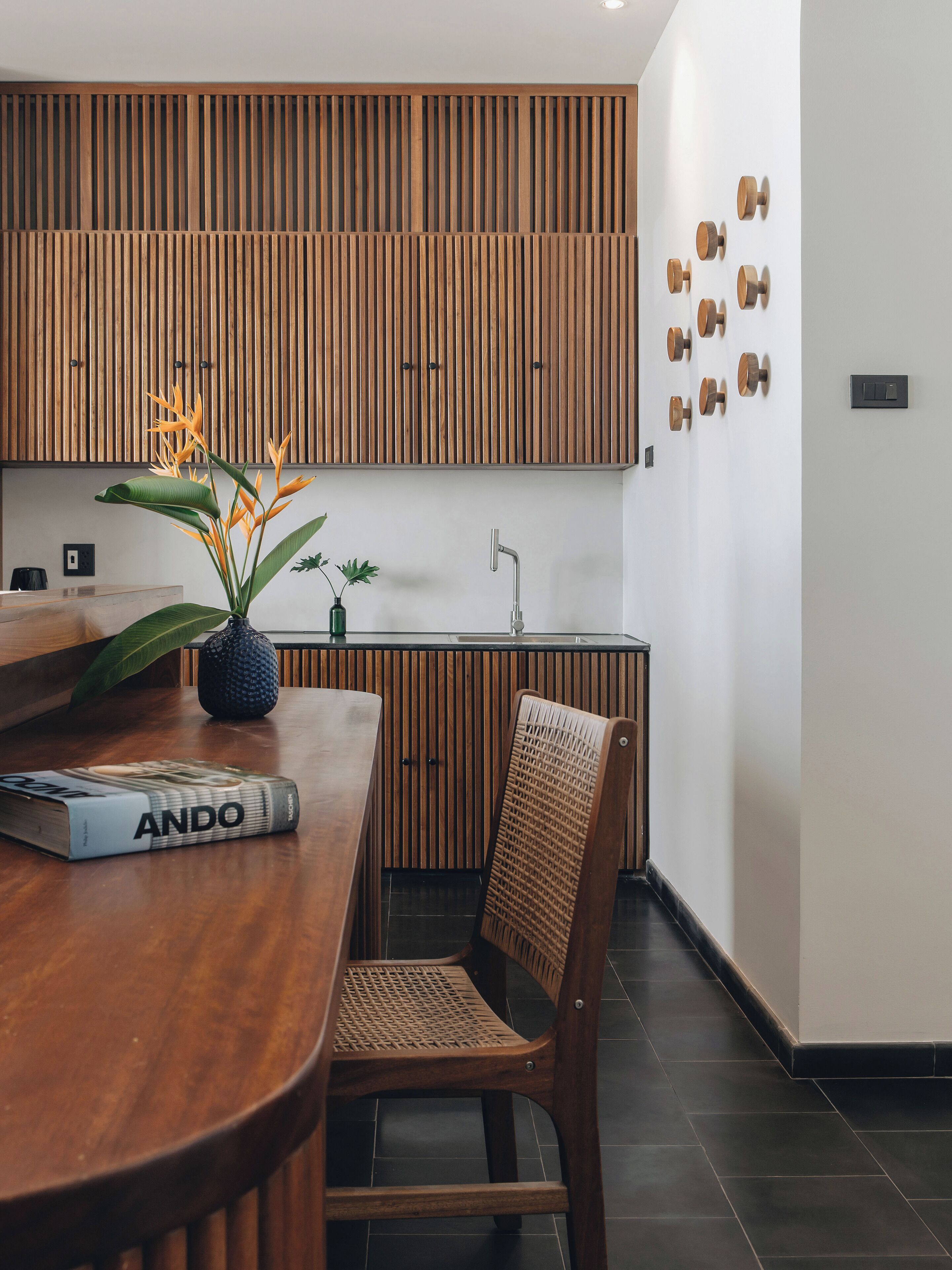 Una cocina moderna con armarios de madera, una mesa de comedor con un libro, una silla y decoración en la pared.
