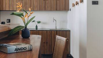 Una cocina moderna con armarios de madera, una mesa de comedor con un libro, una silla y decoración en la pared.