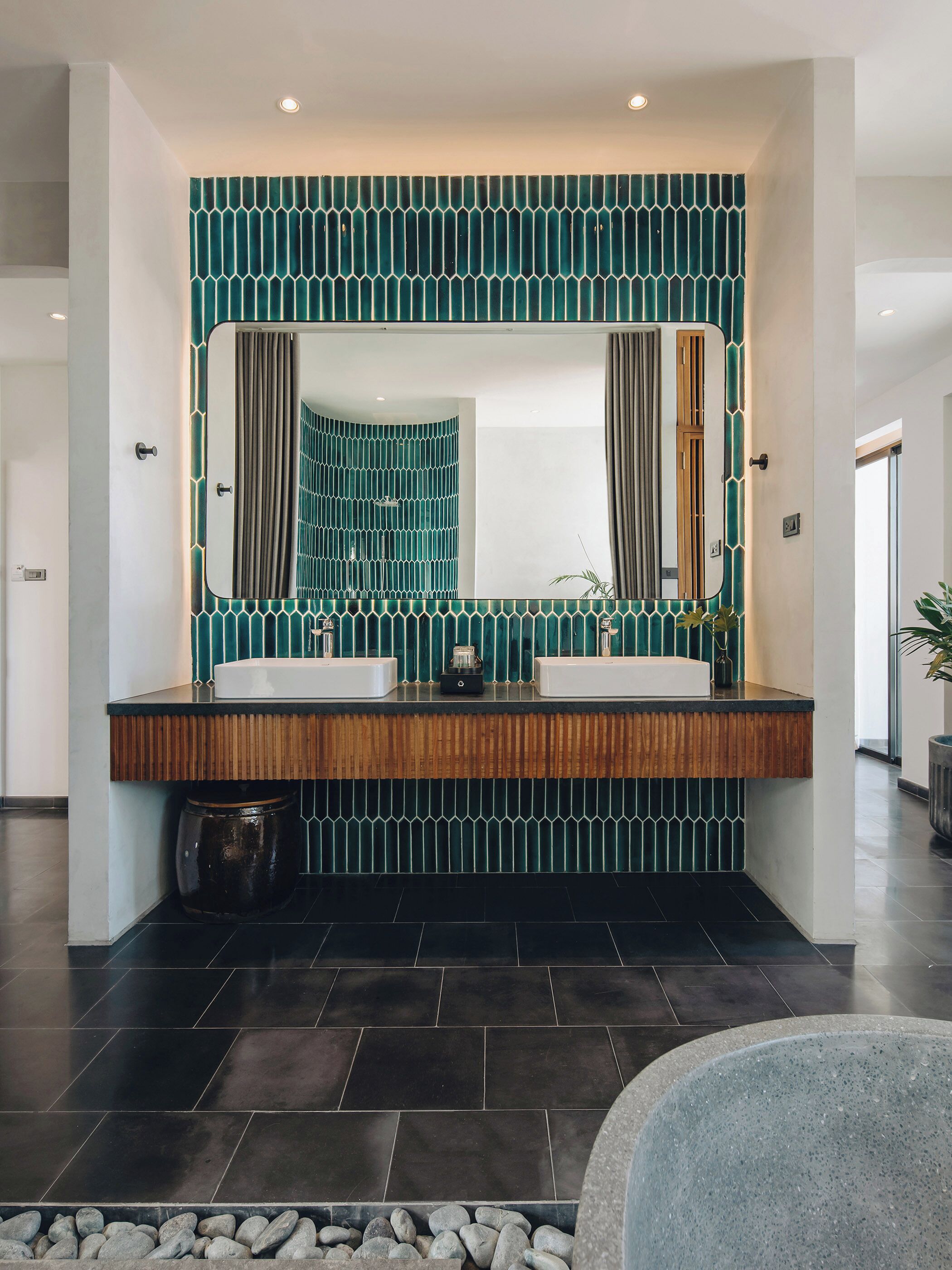 Un baño moderno con un espejo grande, dos lavamanos y un papel tapiz estampado.
