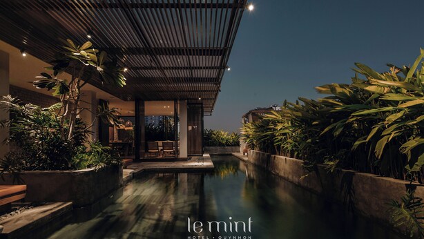 Un hôtel moderne doté d’une piscine, entouré d’une végétation luxuriante et comprenant un espace extérieur couvert.