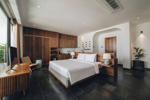 A modern hotel room with a large bed, wooden furniture, a desk, and a view of the outdoors.