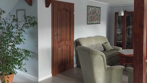 Un salon spacieux avec une porte en bois, un canapé, une petite table et une plante en pot.