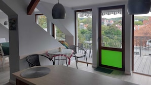 A modern interior with a dining area, a balcony with a view of the city, and a staircase. - Apartment in Sopot Near Monte Cassino Street (Sopot)