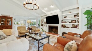 A spacious living room with a fireplace, comfortable seating, and a television mounted on the wall. - Sonny Pointe On the Creek, Steps away from the Beach, Pet Friendly (Georgetown)