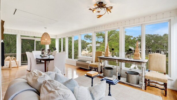 A spacious room with a large window, a dining area, and a cozy seating area with a sofa and chairs. - Sonny Pointe On the Creek, Steps away from the Beach, Pet Friendly (Georgetown)