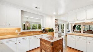 A modern kitchen with white cabinetry, wooden countertops, and a central island. - Sonny Pointe On the Creek, Steps away from the Beach, Pet Friendly (Georgetown)