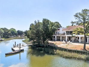 A house with a dock extending into a river, surrounded by trees.
