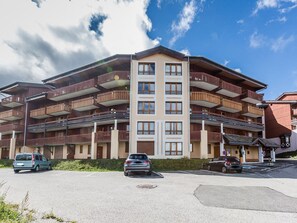 A multi-story hotel with balconies, a parking lot, and a clear sky.