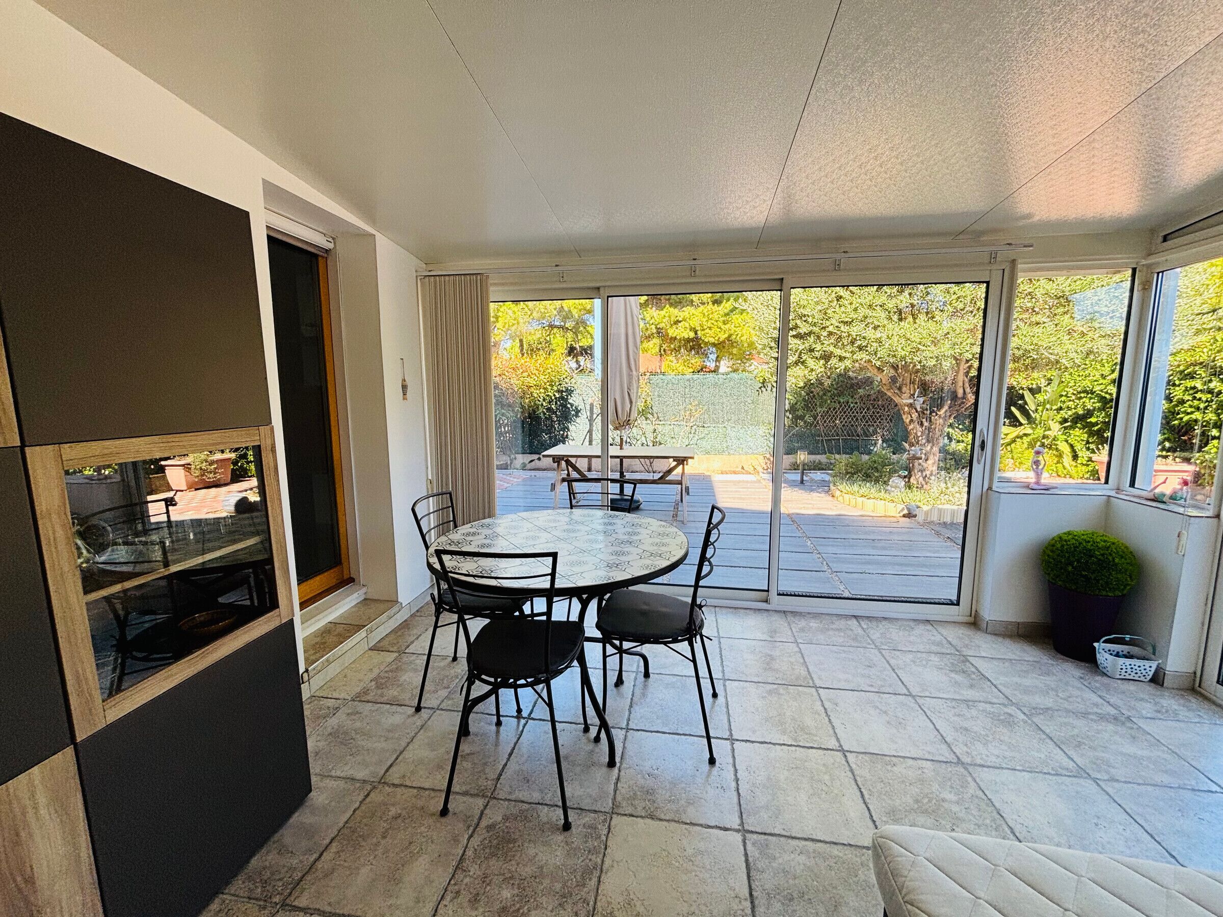 A patio with a table and chairs, a sliding glass door, and a view of the outdoors.