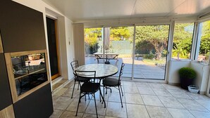 Una veranda con tavolo e sedie, una porta scorrevole in vetro e vista sull'esterno.