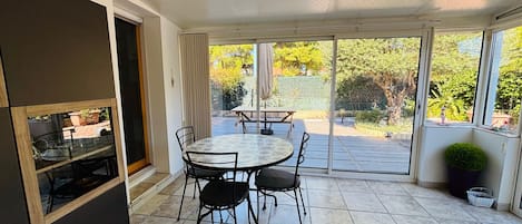 A patio with a table and chairs, a sliding glass door, and a view of the outdoors.