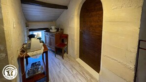 Un couloir étroit avec une porte en bois, une petite table sur laquelle sont posés des ustensiles de cuisine et une fenêtre donnant sur un paysage agréable.
