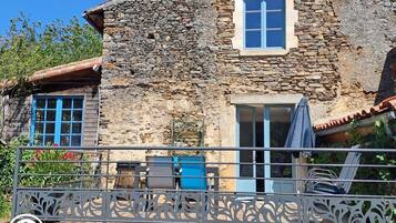 A stone building with a balcony, a window, and a door.