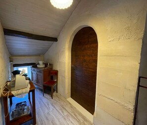A narrow hallway with a wooden door, a small table with kitchenware, and a window with a view.