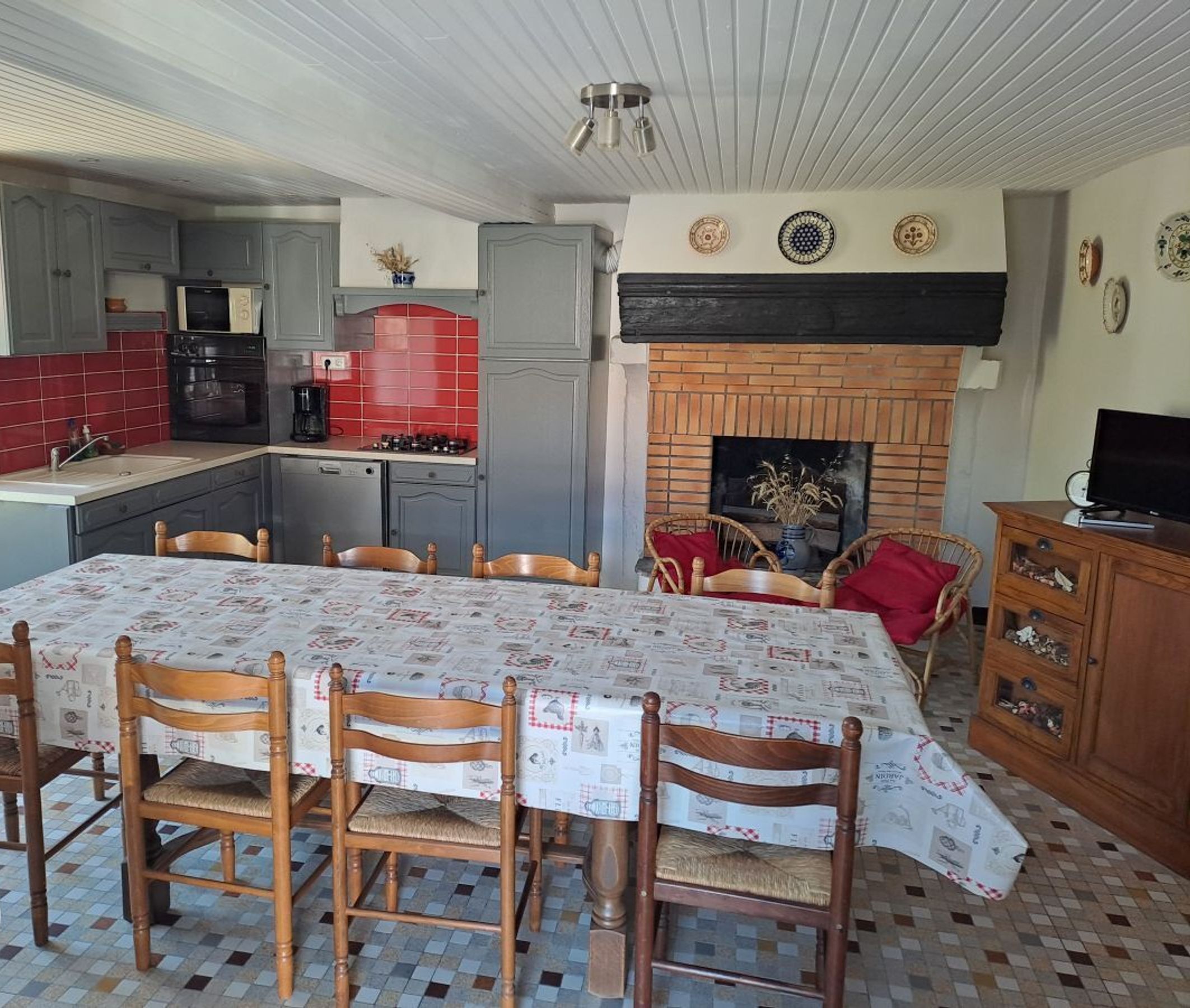Un comedor con una mesa cubierta por un mantel estampado con diseño de periódico, rodeado de sillas de madera.