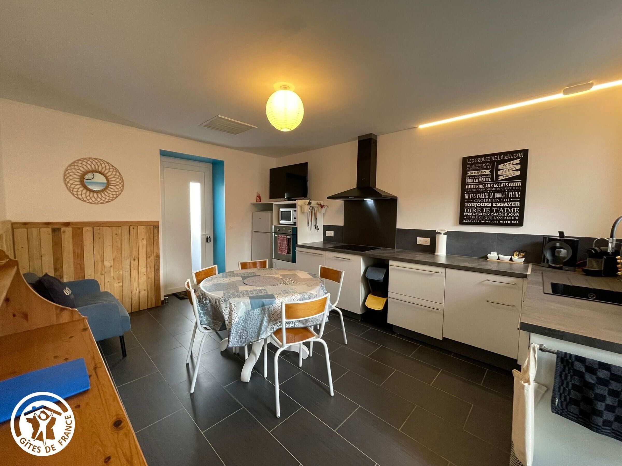 Een moderne keuken met een eetgedeelte, een houten bank en een wandlamp.