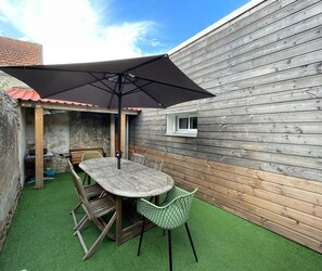 A patio with a table and chairs, an umbrella, and a small window. - Air-conditioned house near the beach in Saint-Hilaire-de-Riez (Saint-Hilaire-de-Riez)