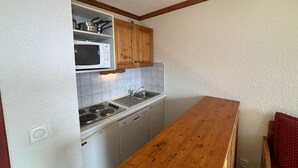 A compact kitchen with white cabinets, a microwave, a sink, and a wooden countertop. - Studio cabin 4 pers. in L'Alpe d'Huez with balcony (Huez)